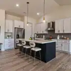Modern white and navy kitchen with island, pendant lighting, and hardwood floors.