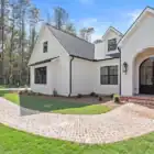 Modern farmhouse style home with white exterior and brick pathway.